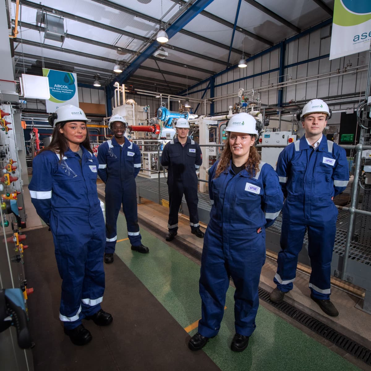 Five APTUS apprentices stand in an oil and gas production training platform.